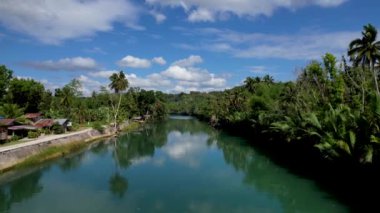 4K Zümrüt Loboc nehrinin nehir kenarındaki yolu ve Bohol, Filipinler 'deki evleri gösteren İHA videosu.