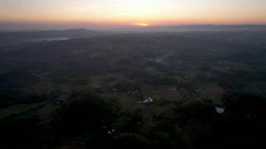 4K Hava Aracı, Bohol, Filipinler 'de eşsiz bir jeolojik oluşum olan Chocolate Hills' in üzerinde büyülü bir güneşin doğuşunu gösteren altın saat videosu.