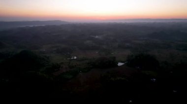 4K Hava Aracı, Bohol, Filipinler 'de eşsiz bir jeolojik oluşum olan Chocolate Hills' in üzerinde büyülü bir güneşin doğuşunu gösteren altın saat videosu.