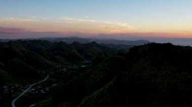 4K Hava Aracı, güzel Kumarhane Tepesi üzerinde büyüleyici bir günbatımı görüntüsü kıyı şeridi manzarası ve etrafındaki sıradağlar ve rüzgarda bir bayrak, Cebu, Filipinler