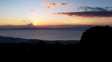 4K Hava Aracı, güzel Kumarhane Tepesi üzerinde büyüleyici bir günbatımı görüntüsü kıyı şeridi manzarası ve etrafındaki sıradağlar ve rüzgarda bir bayrak, Cebu, Filipinler