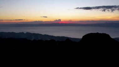 4K Hava Aracı, güzel Kumarhane Tepesi üzerinde büyüleyici bir günbatımı görüntüsü kıyı şeridi manzarası ve etrafındaki sıradağlar ve rüzgarda bir bayrak, Cebu, Filipinler