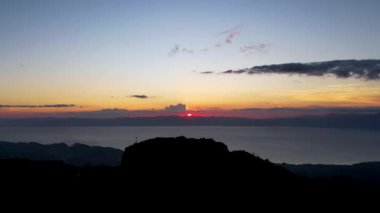 4K Hava Aracı, güzel Kumarhane Tepesi üzerinde büyüleyici bir günbatımı görüntüsü kıyı şeridi manzarası ve etrafındaki sıradağlar ve rüzgarda bir bayrak, Cebu, Filipinler