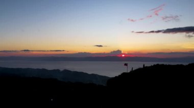 4K Hava Aracı, güzel Kumarhane Tepesi üzerinde büyüleyici bir günbatımı görüntüsü kıyı şeridi manzarası ve etrafındaki sıradağlar ve rüzgarda bir bayrak, Cebu, Filipinler