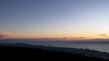 4K Hava Aracı, güzel Kumarhane Tepesi üzerinde büyüleyici bir günbatımı görüntüsü kıyı şeridi manzarası ve etrafındaki sıradağlar ve rüzgarda bir bayrak, Cebu, Filipinler