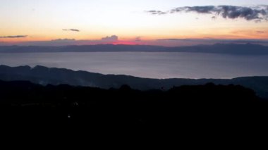 4K Hava Aracı, güzel Kumarhane Tepesi üzerinde büyüleyici bir günbatımı görüntüsü kıyı şeridi manzarası ve etrafındaki sıradağlar ve rüzgarda bir bayrak, Cebu, Filipinler