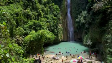 Güzel Mantayupan Şelalesinin güneşli bir günde asma köprüyle çevrili 4K Hava Aracı videosu, Cebu, Filipinler