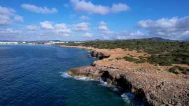 4K Hava Aracı 'nın Mallorca' da kristal berrak suyla çekilmiş videosu güneşli bir yaz gününde sert dalgalar kayalıklara çarpıyor.