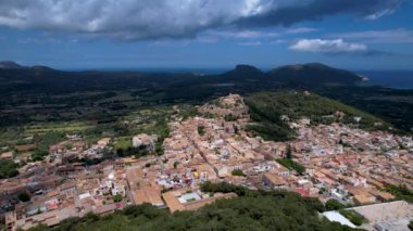 4K Hava Aracı, güneşli bir yaz gününde dağlarla ve denizlerle çevrili tepede devasa bir kalesi olan güzel bir terracotta renkli kasabasının videosu, Capdepera, Mallorca