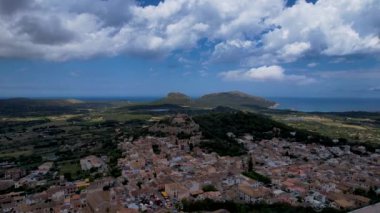 4K Hava Aracı, güneşli bir yaz gününde dağlarla ve denizlerle çevrili tepede devasa bir kalesi olan güzel bir terracotta renkli kasabasının videosu, Capdepera, Mallorca