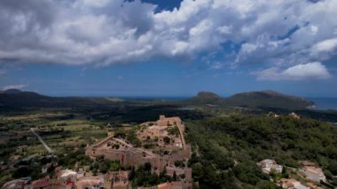 4K Hava Aracı, güneşli bir yaz gününde dağlarla ve denizlerle çevrili tepede devasa bir kalesi olan güzel bir terracotta renkli kasabasının videosu, Capdepera, Mallorca