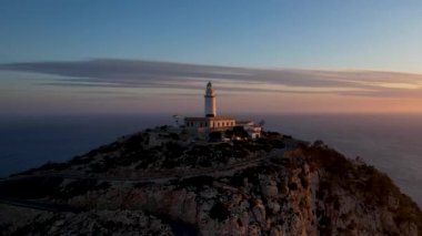 4K Aerial Drone 'un geniş deniz ufkundan yükselen ateşli kırmızı gündoğumu videosu kayalıkların kenarındaki deniz feneri Far of Cap de Formentor, Mallorca, İspanya
