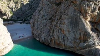 4K Hava Aracı 'nın eşsiz plaj videosu kanyona oyulmuş turkuaz mavi su ve demirli tekneler, Sa Calobra Plajı, Mallorca, İspanya