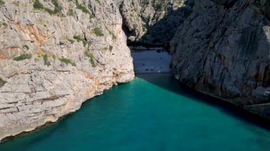 4K Hava Aracı 'nın eşsiz plaj videosu kanyona oyulmuş turkuaz mavi su ve demirli tekneler, Sa Calobra Plajı, Mallorca, İspanya