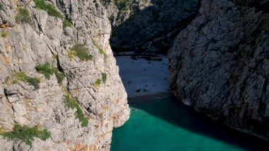 4K Hava Aracı 'nın eşsiz plaj videosu kanyona oyulmuş turkuaz mavi su ve demirli tekneler, Sa Calobra Plajı, Mallorca, İspanya