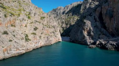 4K Hava Aracı 'nın eşsiz plaj videosu kanyona oyulmuş turkuaz mavi su ve demirli tekneler, Sa Calobra Plajı, Mallorca, İspanya