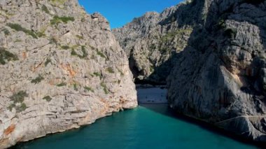 4K Hava Aracı 'nın eşsiz plaj videosu kanyona oyulmuş turkuaz mavi su ve demirli tekneler, Sa Calobra Plajı, Mallorca, İspanya