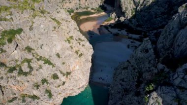 4K Hava Aracı 'nın eşsiz plaj videosu kanyona oyulmuş turkuaz mavi su ve demirli tekneler, Sa Calobra Plajı, Mallorca, İspanya