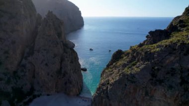 4K Hava Aracı 'nın eşsiz plaj videosu kanyona oyulmuş turkuaz mavi su ve demirli tekneler, Sa Calobra Plajı, Mallorca, İspanya