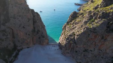 4K Hava Aracı 'nın eşsiz plaj videosu kanyona oyulmuş turkuaz mavi su ve demirli tekneler, Sa Calobra Plajı, Mallorca, İspanya