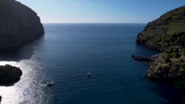 4K Hava Aracı 'nın eşsiz plaj videosu kanyona oyulmuş turkuaz mavi su ve demirli tekneler, Sa Calobra Plajı, Mallorca, İspanya