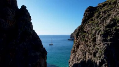 4K Hava Aracı 'nın eşsiz plaj videosu kanyona oyulmuş turkuaz mavi su ve demirli tekneler, Sa Calobra Plajı, Mallorca, İspanya