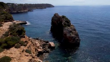 4K Hava Aracı 'nın eşsiz bir kaya oluşumunun videosu. Kayalıklardan ayrılan bir kemer. Yakınındaki turkuaz berrak mavi su ve plajla birlikte. Es Pontas, Mallorca