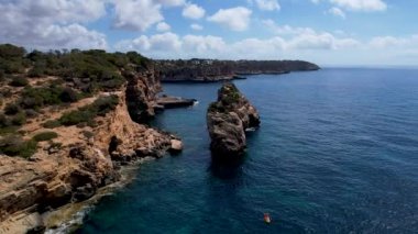 4K Hava Aracı 'nın eşsiz bir kaya oluşumunun videosu. Kayalıklardan ayrılan bir kemer. Yakınındaki turkuaz berrak mavi su ve plajla birlikte. Es Pontas, Mallorca
