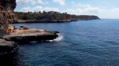 4K Hava Aracı 'nın eşsiz bir kaya oluşumunun videosu. Kayalıklardan ayrılan bir kemer. Yakınındaki turkuaz berrak mavi su ve plajla birlikte. Es Pontas, Mallorca