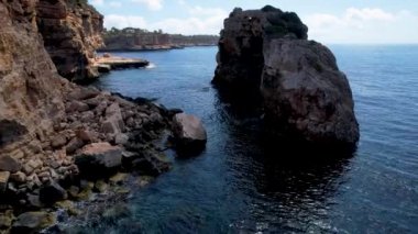 4K Hava Aracı 'nın eşsiz bir kaya oluşumunun videosu. Kayalıklardan ayrılan bir kemer. Yakınındaki turkuaz berrak mavi su ve plajla birlikte. Es Pontas, Mallorca
