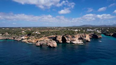 4K Hava Aracı 'nın eşsiz bir kaya oluşumunun videosu. Kayalıklardan ayrılan bir kemer. Yakınındaki turkuaz berrak mavi su ve plajla birlikte. Es Pontas, Mallorca