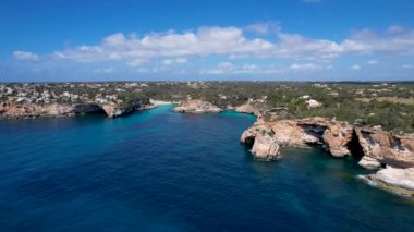 4K Hava Aracı 'nın eşsiz bir kaya oluşumunun videosu. Kayalıklardan ayrılan bir kemer. Yakınındaki turkuaz berrak mavi su ve plajla birlikte. Es Pontas, Mallorca