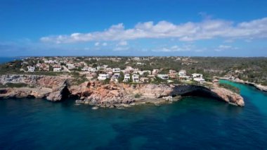 4K Hava Aracı 'nın eşsiz bir kaya oluşumunun videosu. Kayalıklardan ayrılan bir kemer. Yakınındaki turkuaz berrak mavi su ve plajla birlikte. Es Pontas, Mallorca
