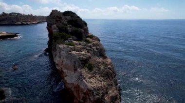 4K Hava Aracı 'nın eşsiz bir kaya oluşumunun videosu. Kayalıklardan ayrılan bir kemer. Yakınındaki turkuaz berrak mavi su ve plajla birlikte. Es Pontas, Mallorca