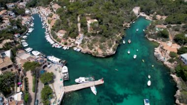 4K Hava Aracı, küçük bir balıkçı kasabasının videosu, kristal berrak turkuaz suyu olan balıkçı tekneleri, Cala Figuera, Mallorca