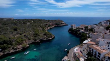 4K Hava Aracı, küçük bir balıkçı kasabasının videosu, kristal berrak turkuaz suyu olan balıkçı tekneleri, Cala Figuera, Mallorca