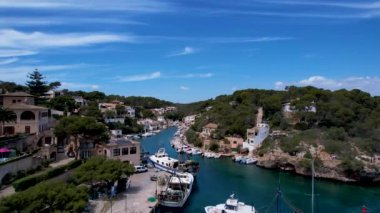 4K Hava Aracı, küçük bir balıkçı kasabasının videosu, kristal berrak turkuaz suyu olan balıkçı tekneleri, Cala Figuera, Mallorca