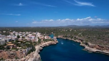 4K Hava Aracı, küçük bir balıkçı kasabasının videosu, kristal berrak turkuaz suyu olan balıkçı tekneleri, Cala Figuera, Mallorca