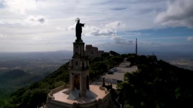 4K Hava Aracı video destansı heykel, tepenin üstünde çapraz ve manastır güneşli bir günde, Sant Salvador Sığınak ve Puig, Mallorca