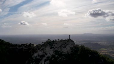 4K Hava Aracı video destansı heykel, tepenin üstünde çapraz ve manastır güneşli bir günde, Sant Salvador Sığınak ve Puig, Mallorca