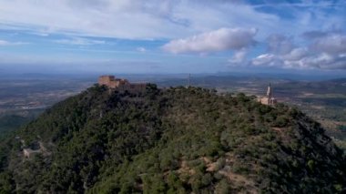 4K Hava Aracı video destansı heykel, tepenin üstünde çapraz ve manastır güneşli bir günde, Sant Salvador Sığınak ve Puig, Mallorca