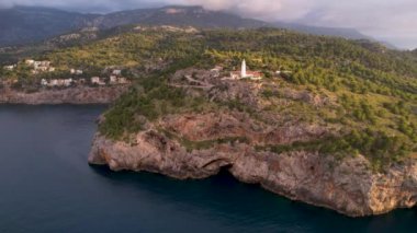 Popüler yaz mevsiminin 4K Aerial Drone videosu, uçurumların üzerinde gün batımı bir deniz feneri ve büyük bir liman dolusu martıların uçtuğu altın saat. Port de Soller, Mallorca