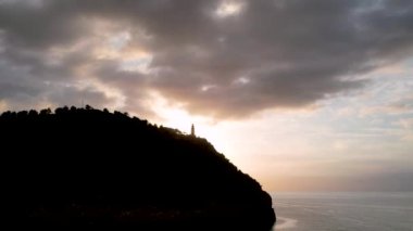Popüler yaz mevsiminin 4K Aerial Drone videosu, uçurumların üzerinde gün batımı bir deniz feneri ve büyük bir liman dolusu martıların uçtuğu altın saat. Port de Soller, Mallorca