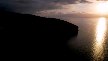 Popüler yaz mevsiminin 4K Aerial Drone videosu, uçurumların üzerinde gün batımı bir deniz feneri ve büyük bir liman dolusu martıların uçtuğu altın saat. Port de Soller, Mallorca