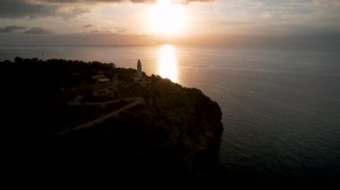 Popüler yaz mevsiminin 4K Aerial Drone videosu, uçurumların üzerinde gün batımı bir deniz feneri ve büyük bir liman dolusu martıların uçtuğu altın saat. Port de Soller, Mallorca