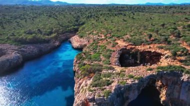 4K Hava Aracı 'nın en inanılmaz turkuaz mavi su renginde kayalık bir formasyon ve güneşli bir yaz gününde demirlenmiş tekneler Cala Varques, Mallorca' da gözlerden uzak bir plaj.