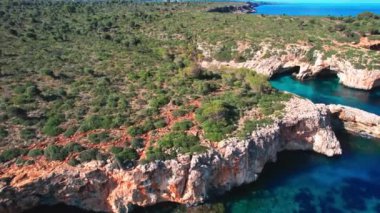 4K Hava Aracı 'nın en inanılmaz turkuaz mavi su renginde kayalık bir formasyon ve güneşli bir yaz gününde demirlenmiş tekneler Cala Varques, Mallorca' da gözlerden uzak bir plaj.