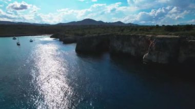 4K Hava Aracı 'nın en inanılmaz turkuaz mavi su renginde kayalık bir formasyon ve güneşli bir yaz gününde demirlenmiş tekneler Cala Varques, Mallorca' da gözlerden uzak bir plaj.