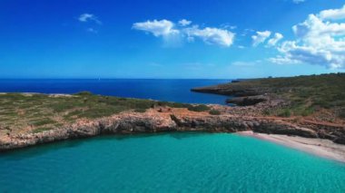 4K Hava Aracı 'nın en inanılmaz turkuaz mavi su renginde kayalık bir formasyon ve güneşli bir yaz gününde demirlenmiş tekneler Cala Varques, Mallorca' da gözlerden uzak bir plaj.