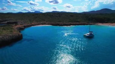 4K Hava Aracı 'nın en inanılmaz turkuaz mavi su renginde kayalık bir formasyon ve güneşli bir yaz gününde demirlenmiş tekneler Cala Varques, Mallorca' da gözlerden uzak bir plaj.